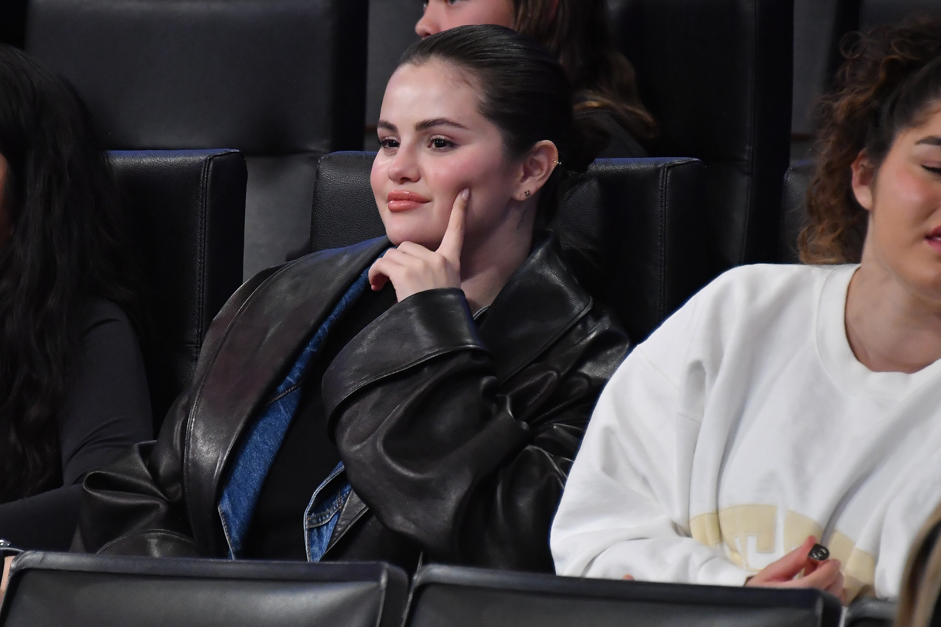 Close-up of Selena sitting with a friend in an audience