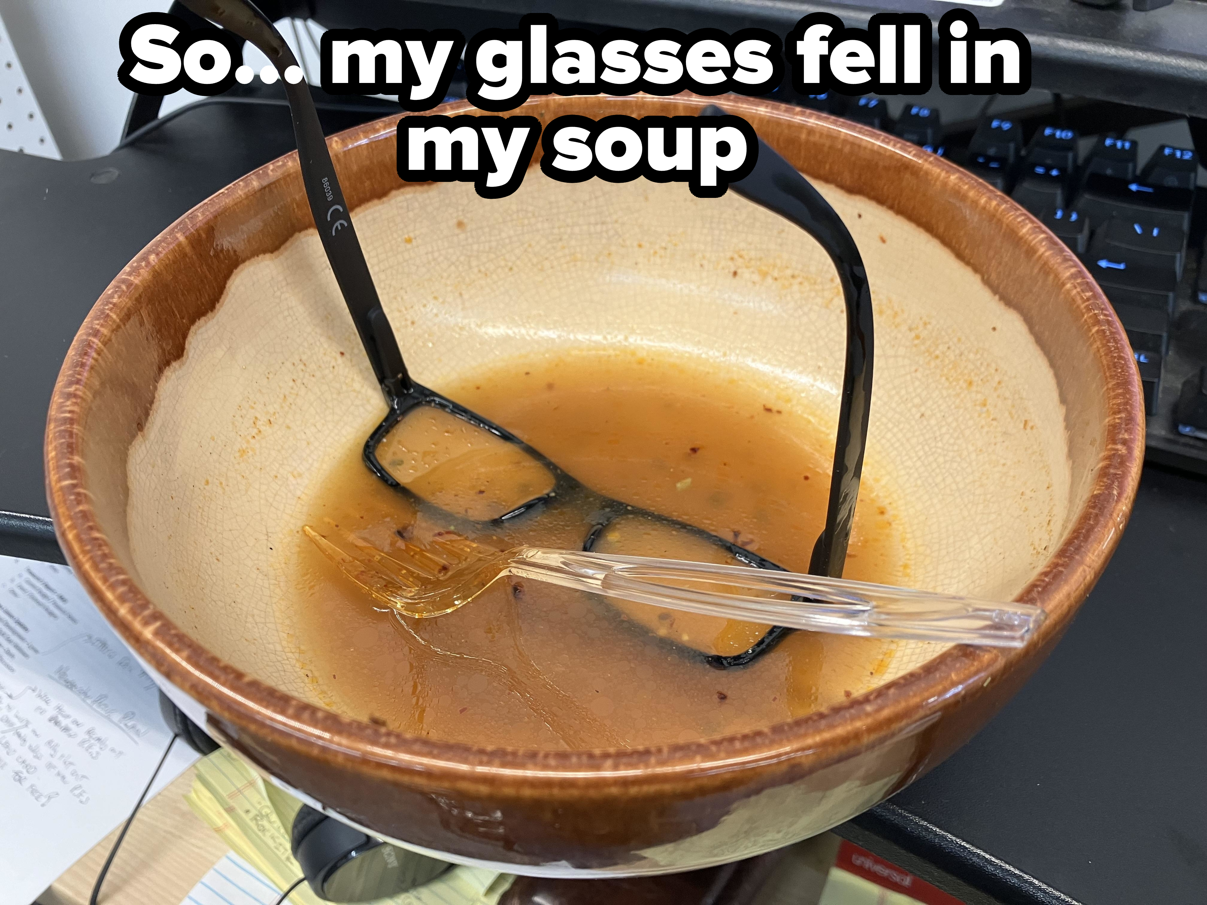 A pair of glasses sits in a bowl of almost finished soup