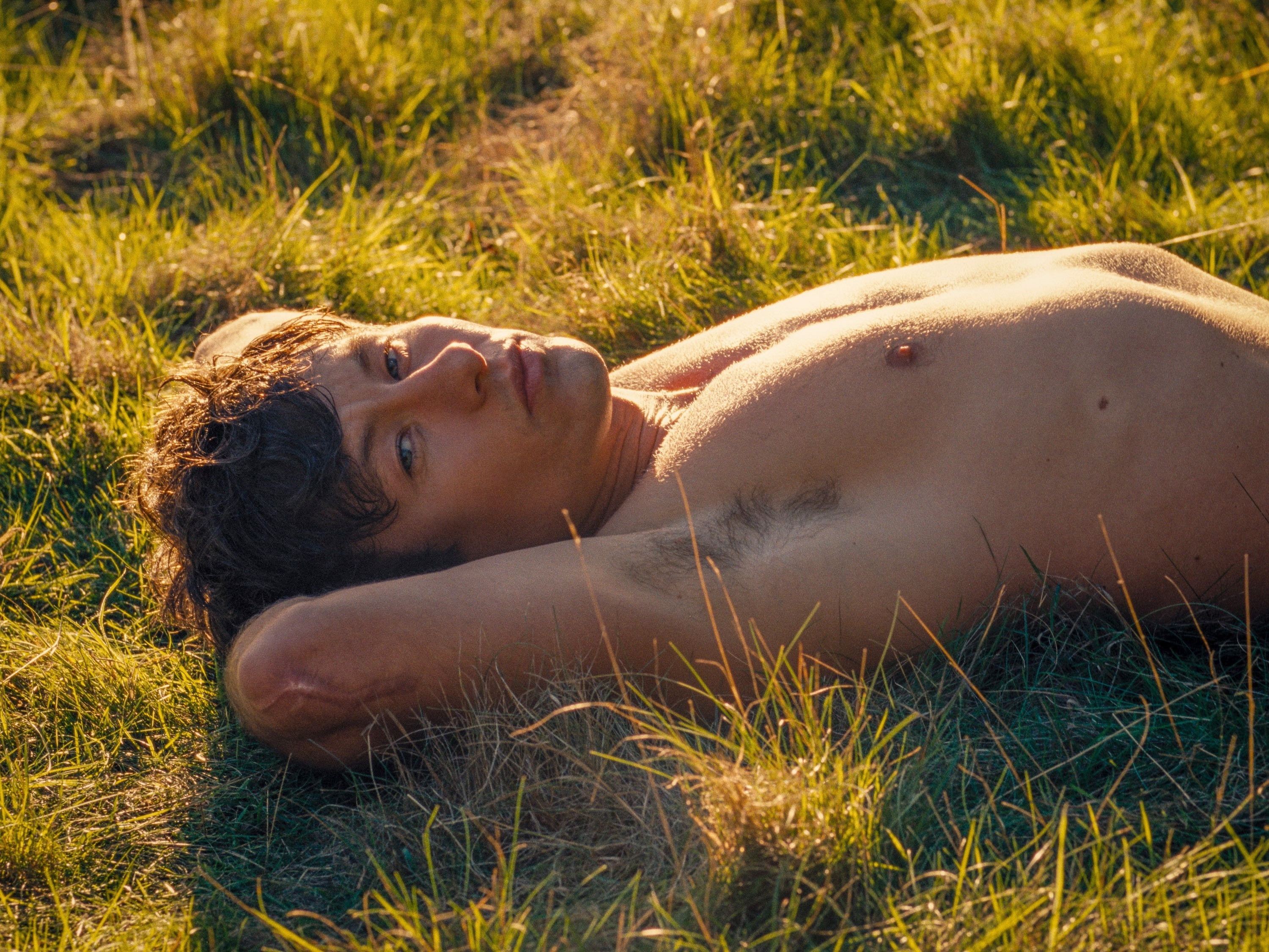 Oliver lies shirtless in the grass in a scene from &quot;Saltburn&quot;