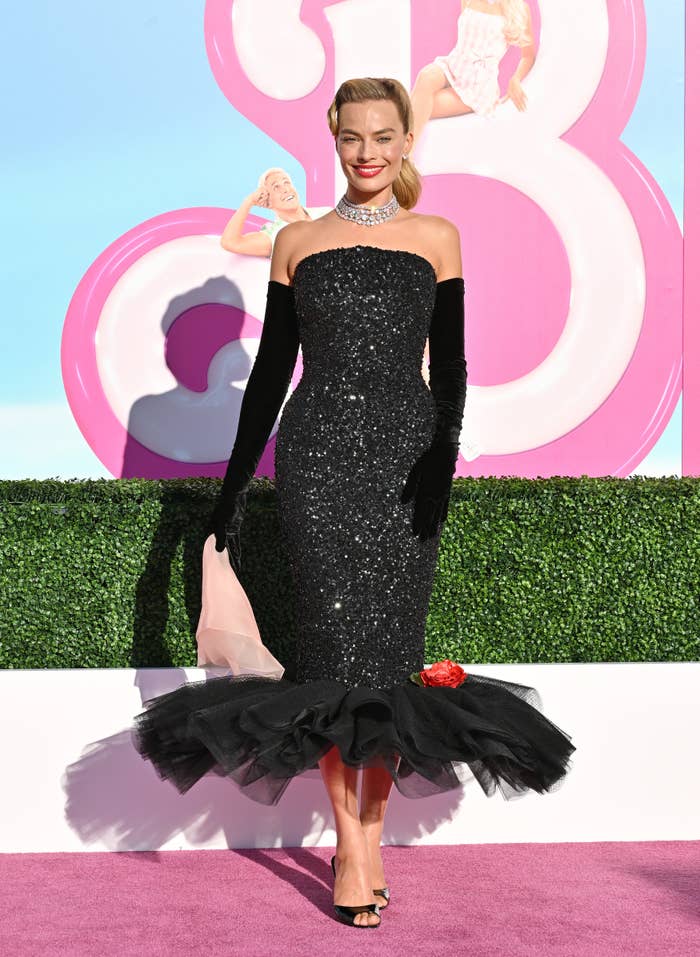 Margot Robbie on the Barbie pink carpet in a short sequined dress with a tulle bottom and opera gloves