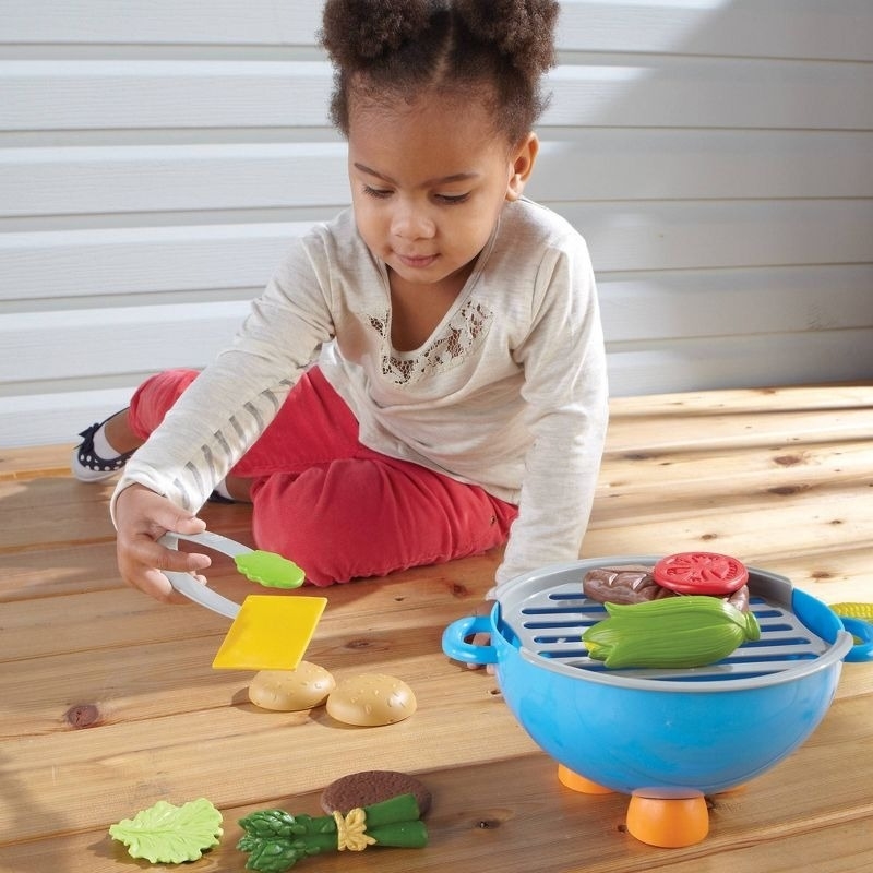 A child plays with a toy grilling set