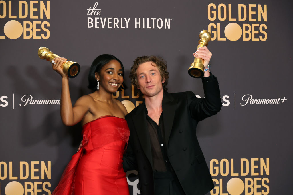 Ayo Edebiri and Jeremy Allen White holding up their Golden Globes