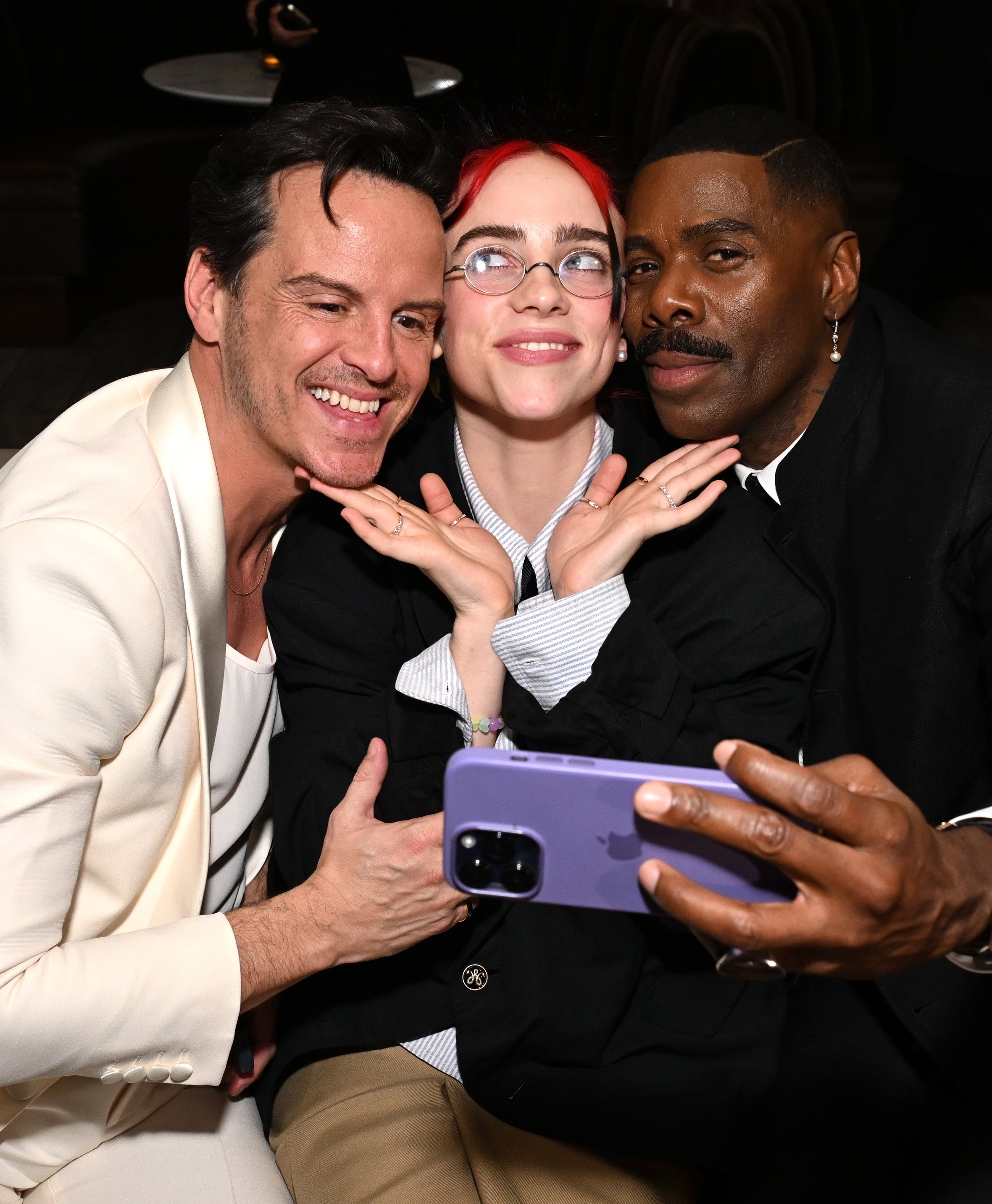 Billie playfully smiles as she sits in between Paul and Colman who is taking the selfie