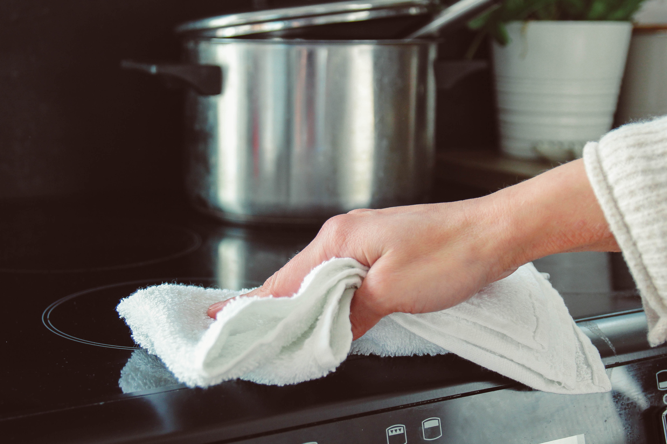 Someone wiping down a stove top with a dish cloth