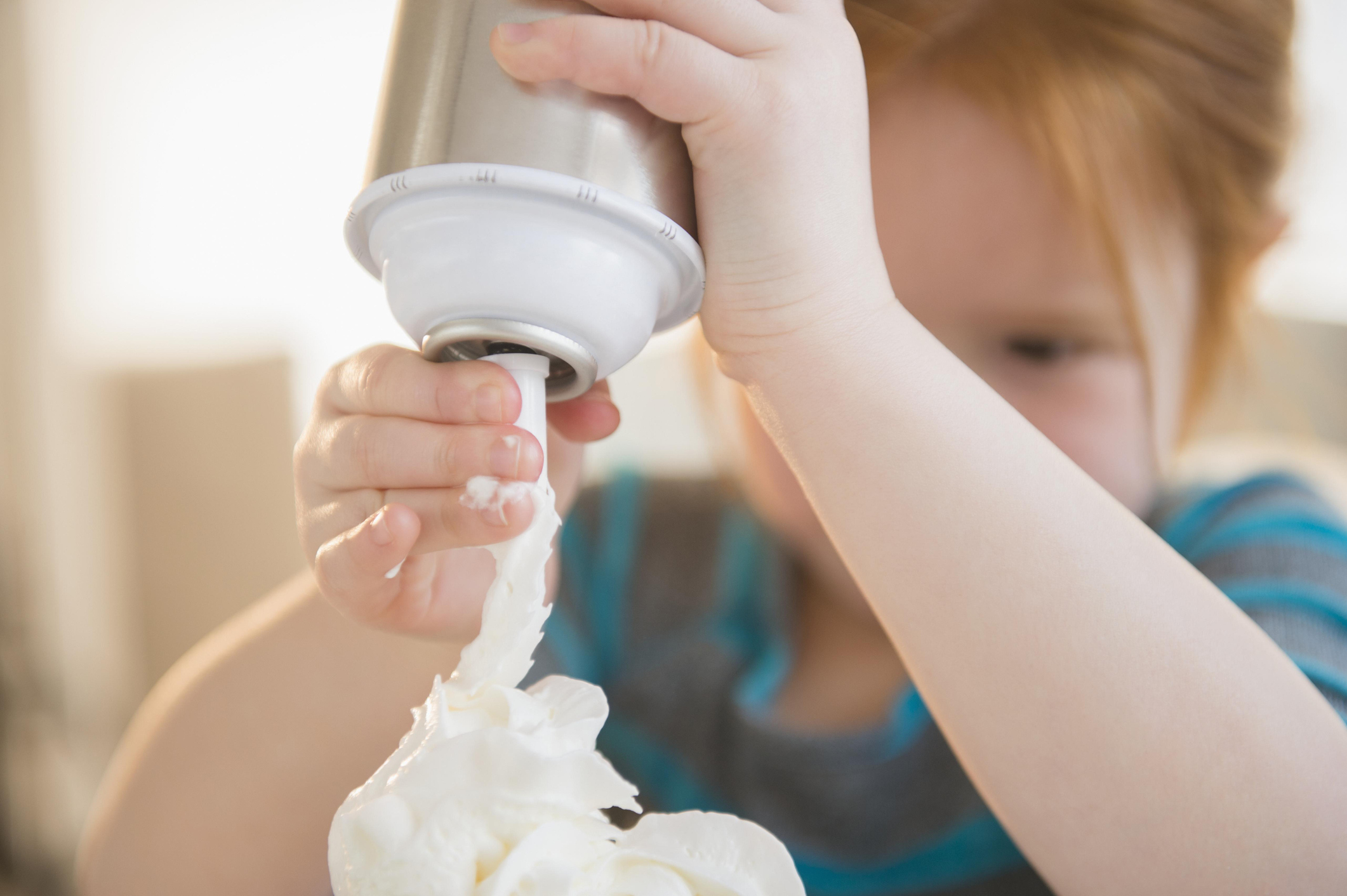 A child spraying whipped cream out of a can