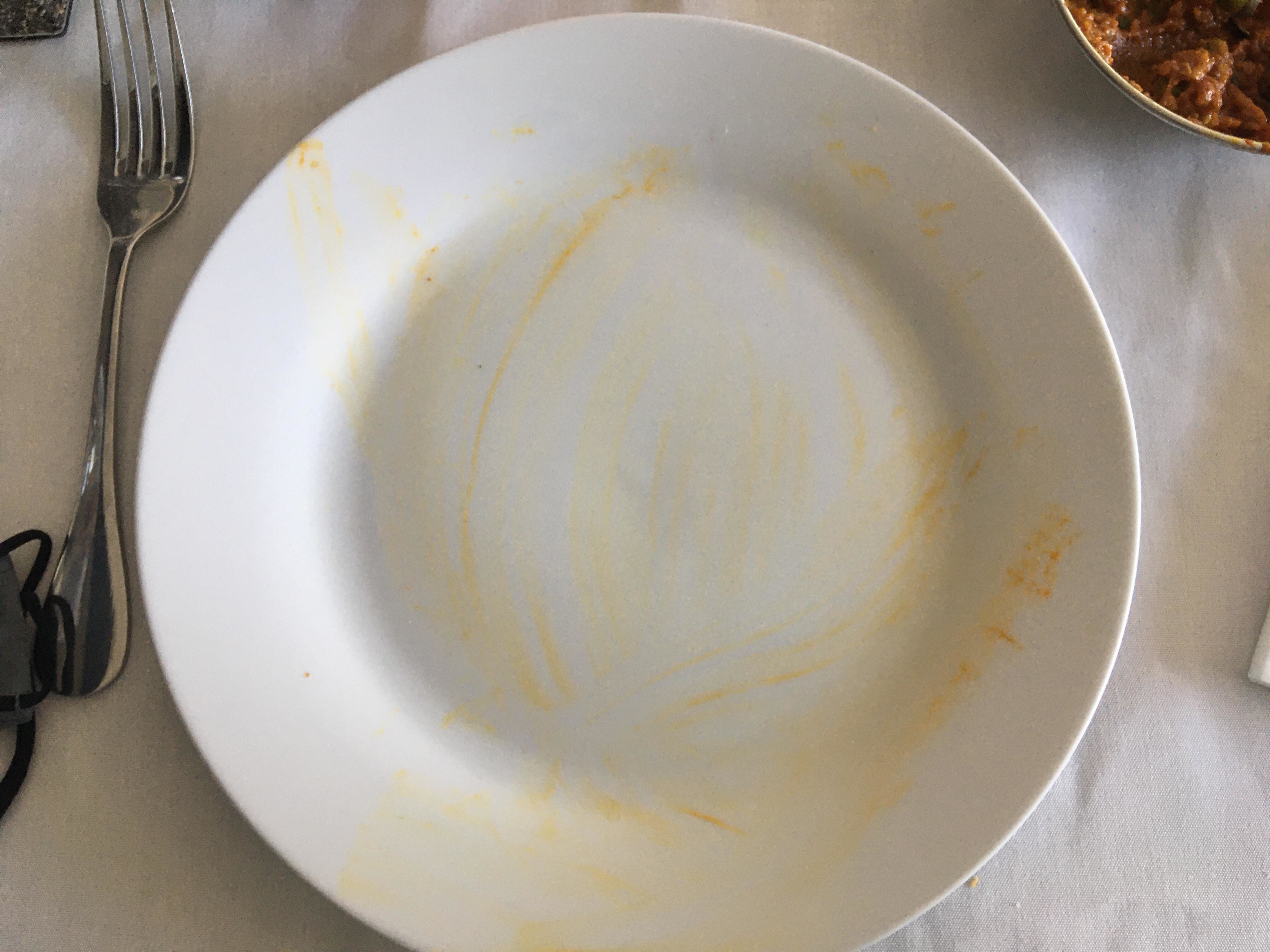 An empty plate with streaks of food residue still on it