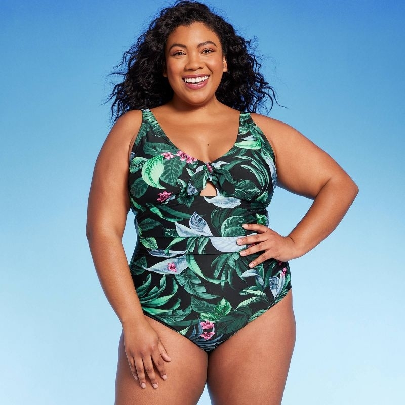 Model wearing the green leaf and pink flower-print swimsuit