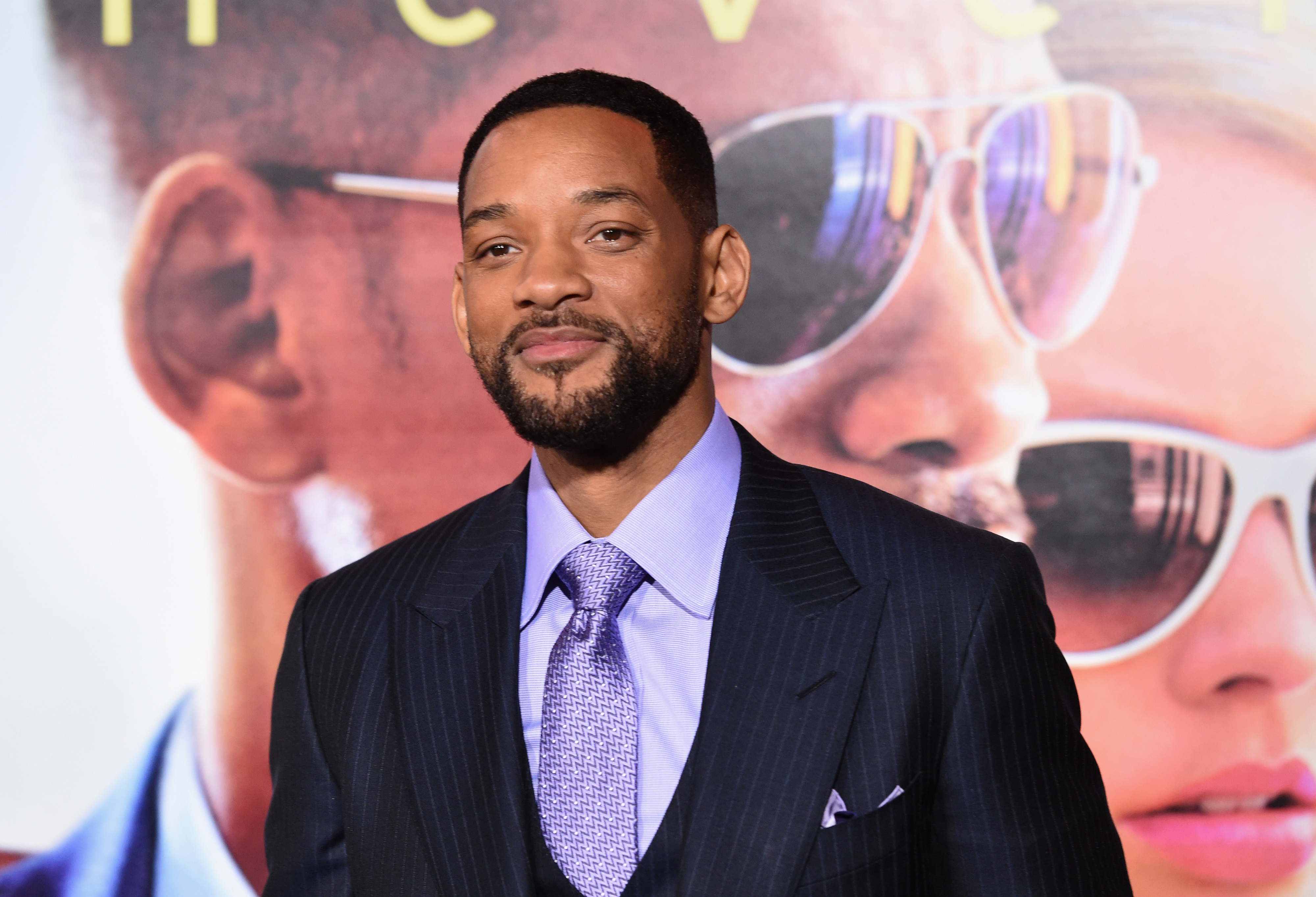 Will Smith smiles on the red carpet as he wears a suit and tie