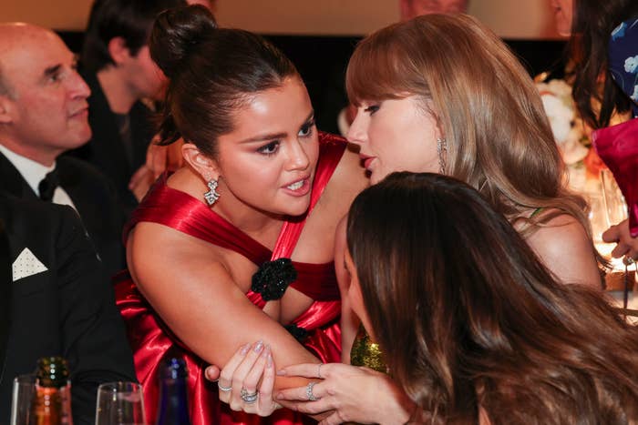 selena leaning over to talk to taylor swift