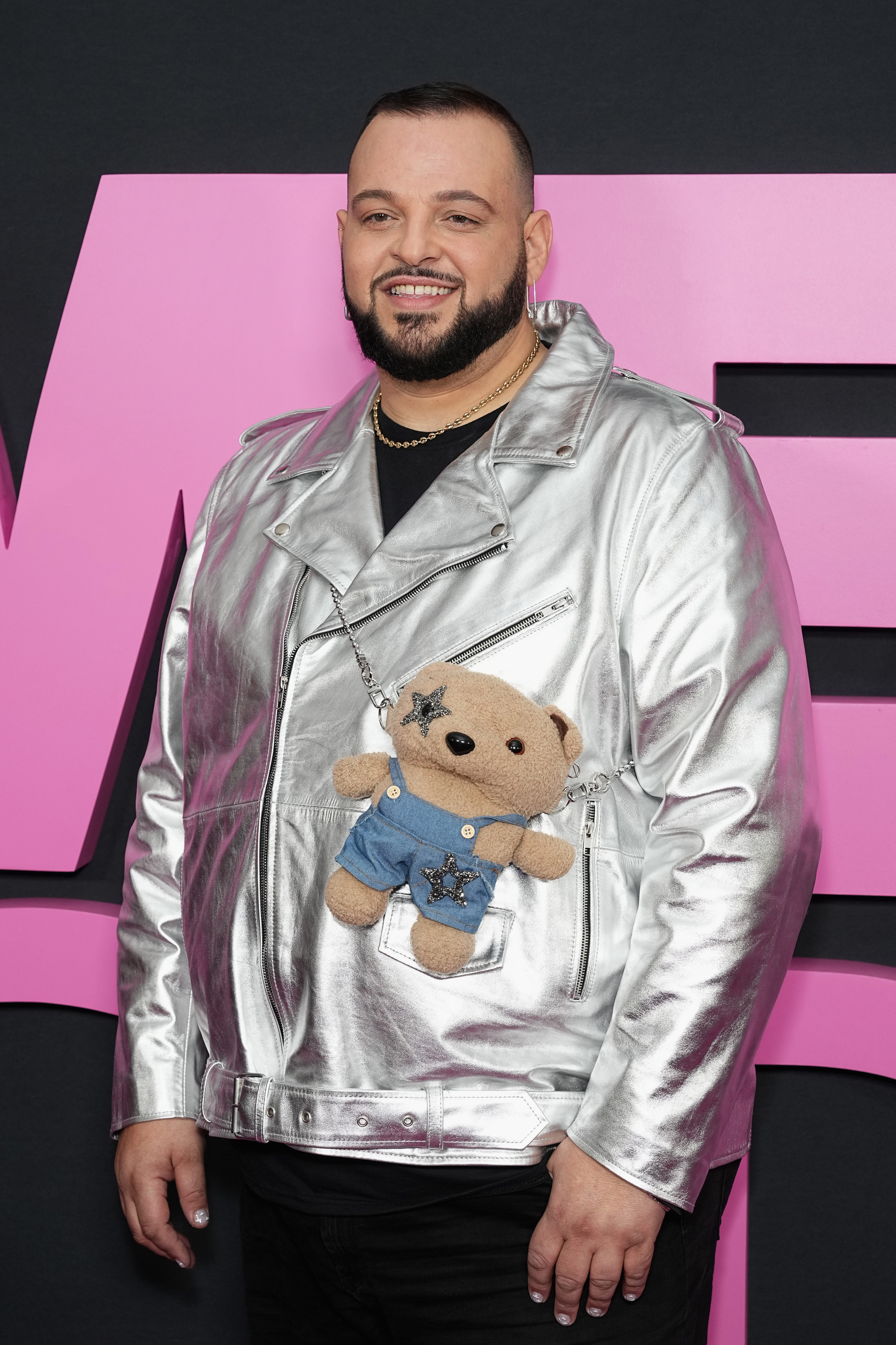 he's in a metallic jacket with a crossbody bear