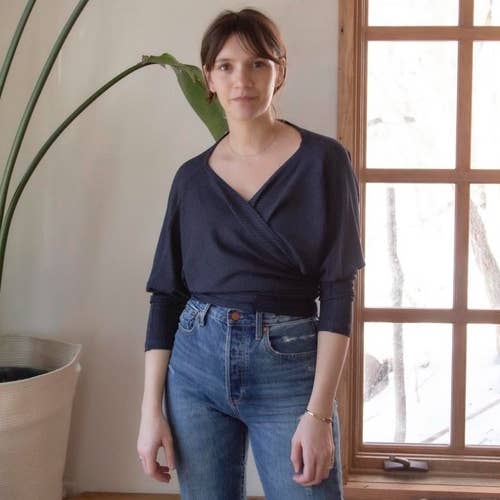 a model wearing the shirt in navy as a wrap top with a surplice neckline