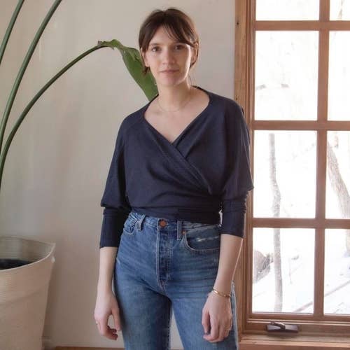 a model wearing the shirt in navy as a wrap top with a surplice neckline