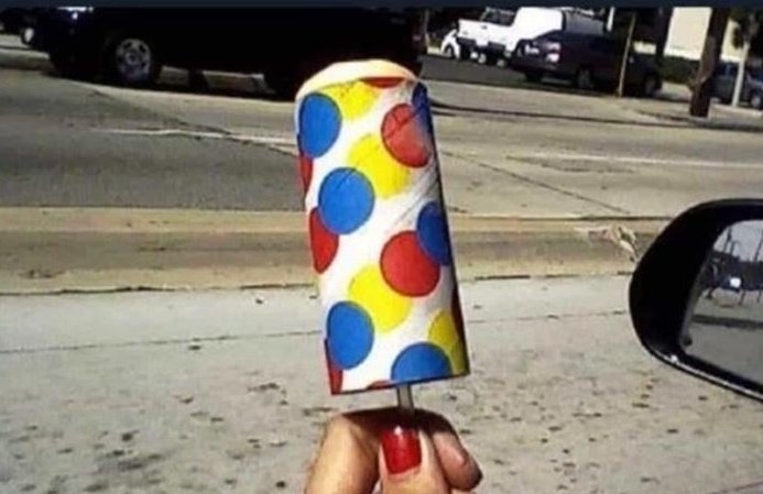 An ice cream on a stick in a tube with multicolored circles on it