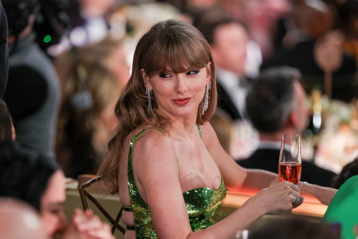 Close-up of Taylor holding a beverage and wearing a sparkly sleeveless outfit