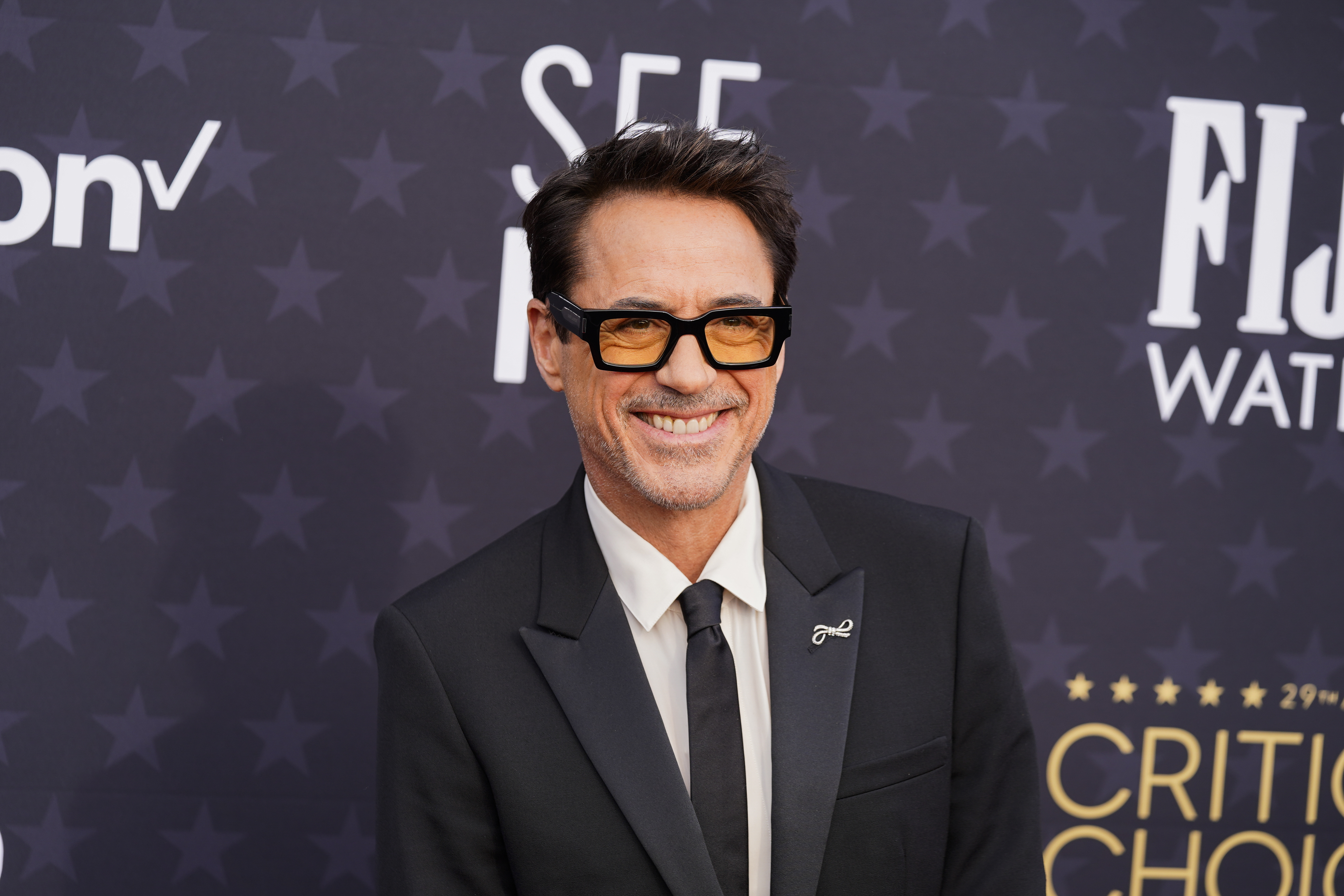 Close-up of RDJ in a suit and tie smiling at a media event