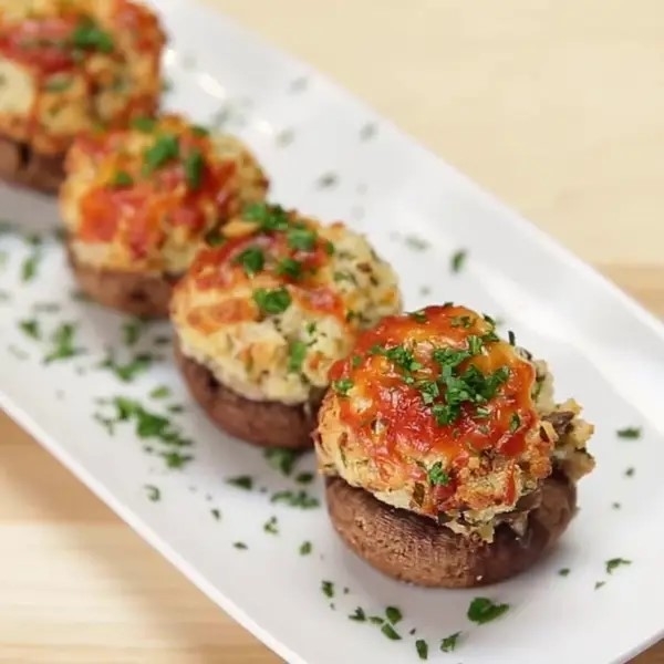 Stuffed mushrooms topped with herbs and sauce on a plate