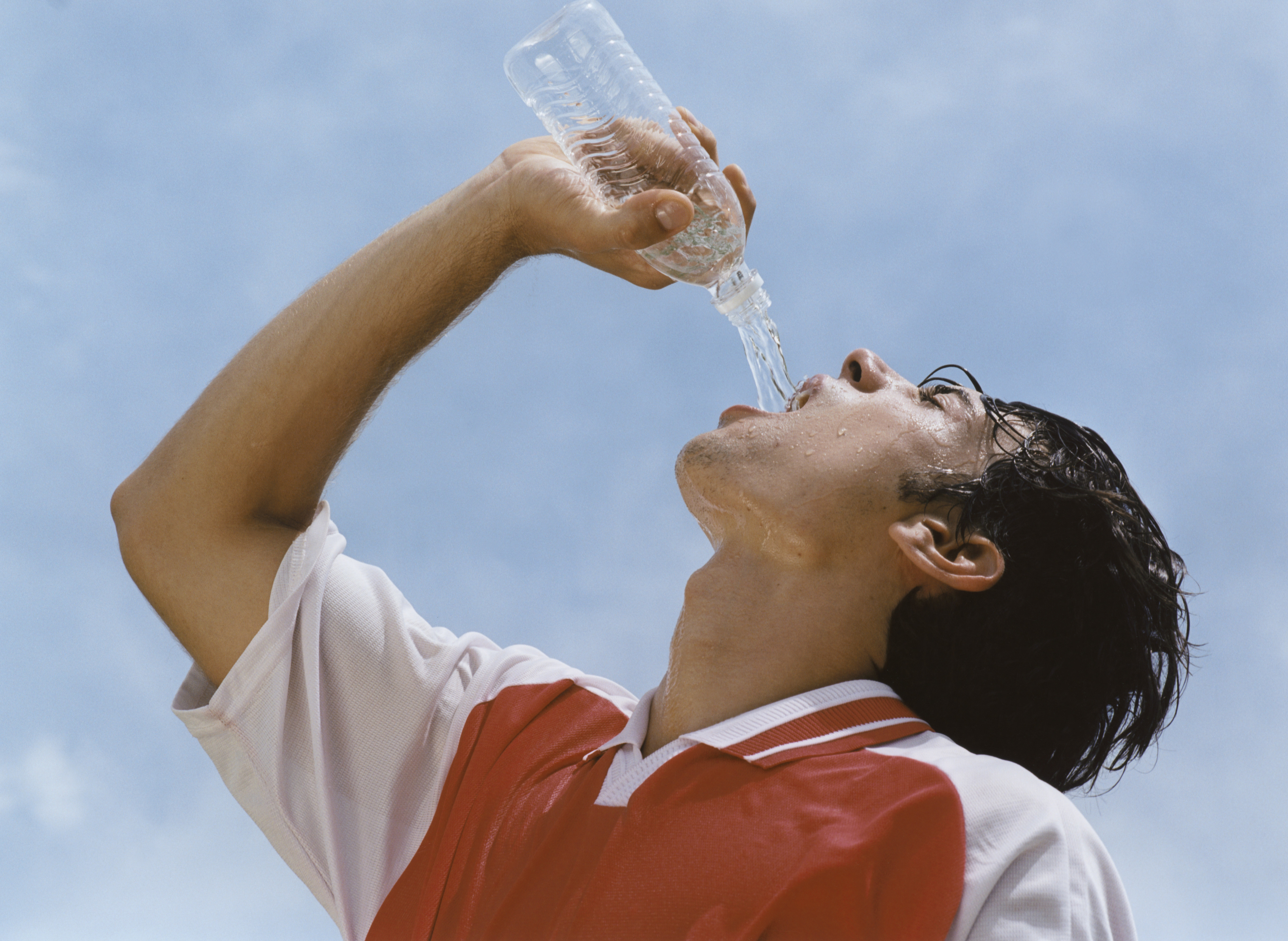 A sweaty man drinking bottled water