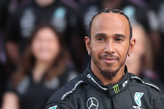 Lewis Hamilton, driver for Mercedes Formula 1 team, donning his race attire with a smirk