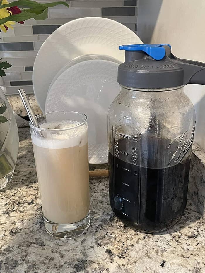 The cold brew maker next to a cup of coffee