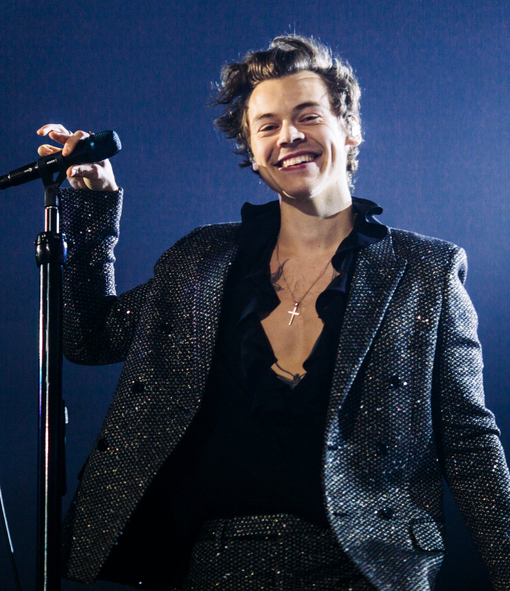 he&#x27;s smiling on stage with a sparkly suit and unruly hair