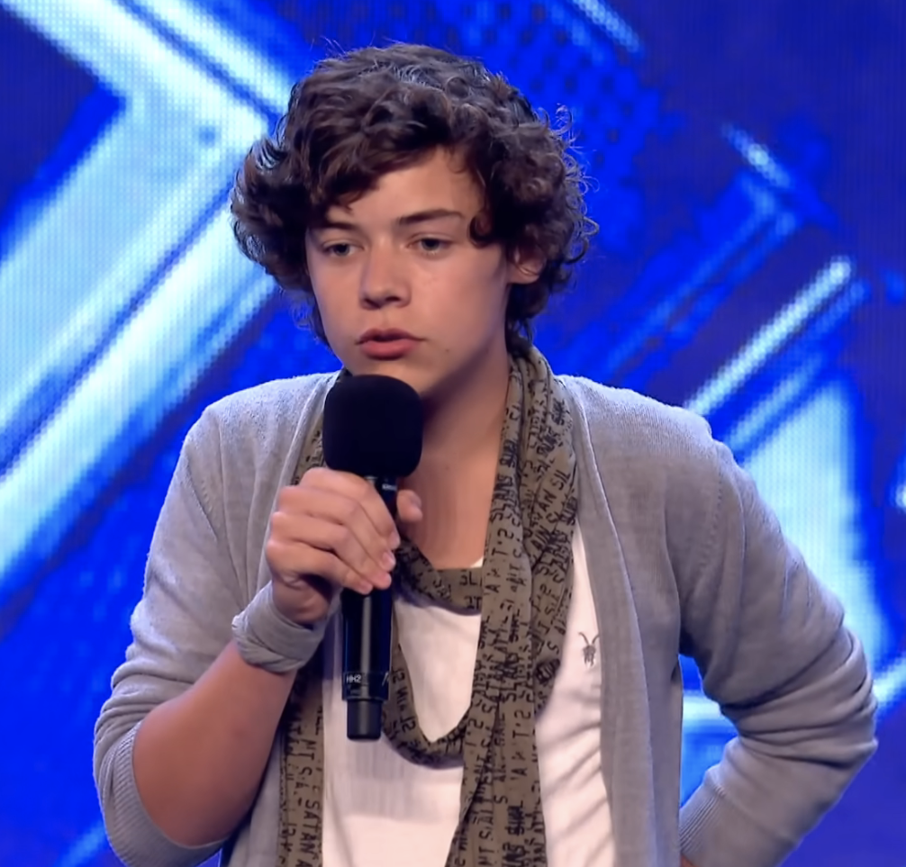 young harry wearing a skinny scarf and talking into a mic