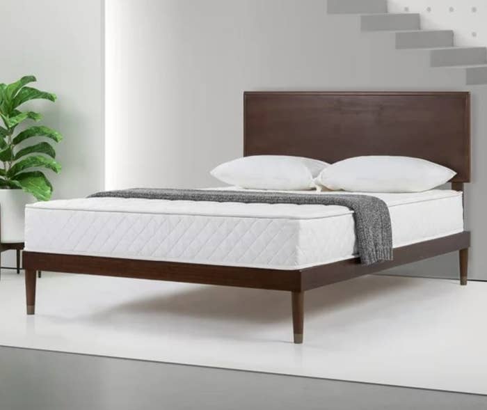 dark brown wooden bedframe with mattress and pillows