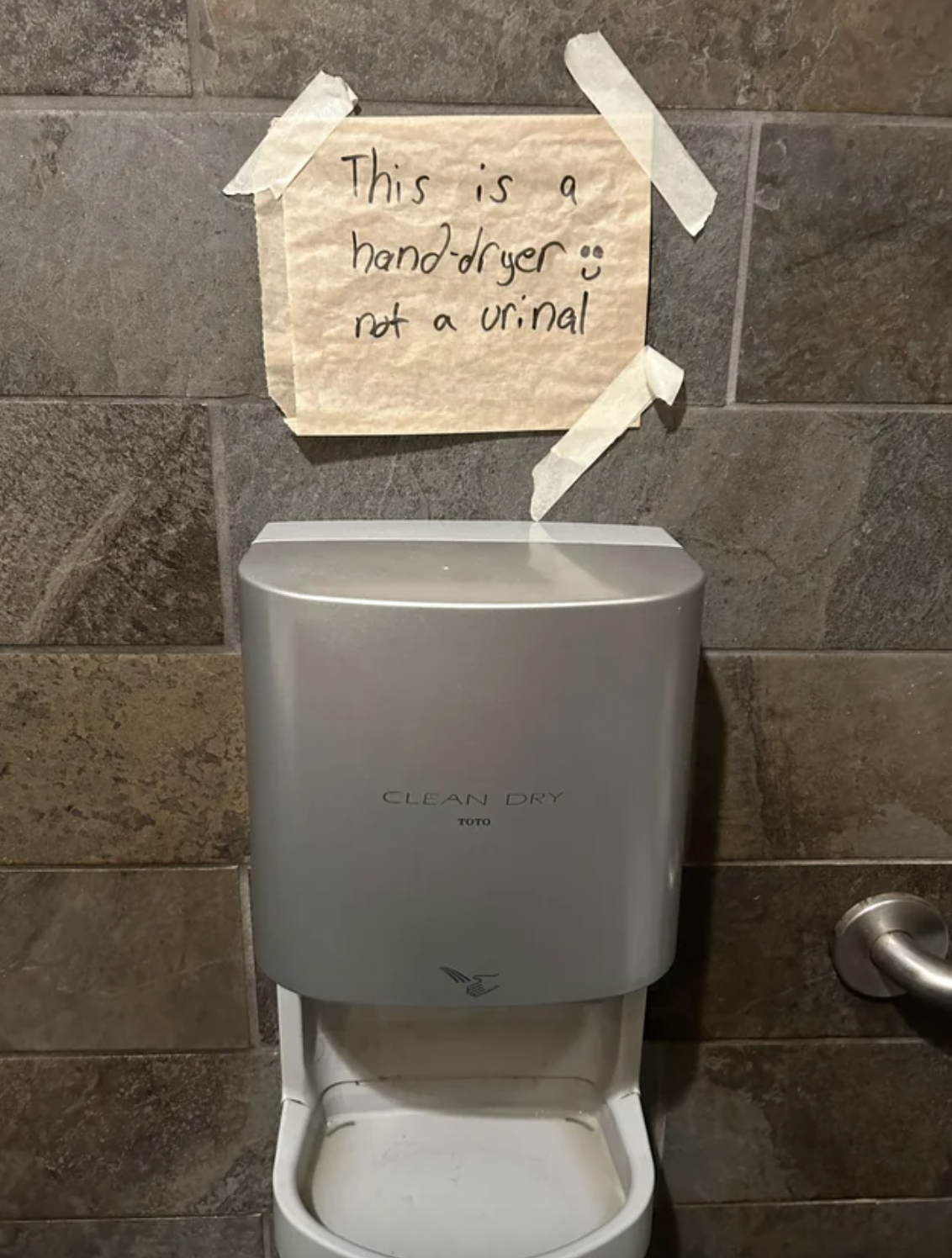 &quot;This is a hand dryer not a urinal&quot; above what looks like a small urinal