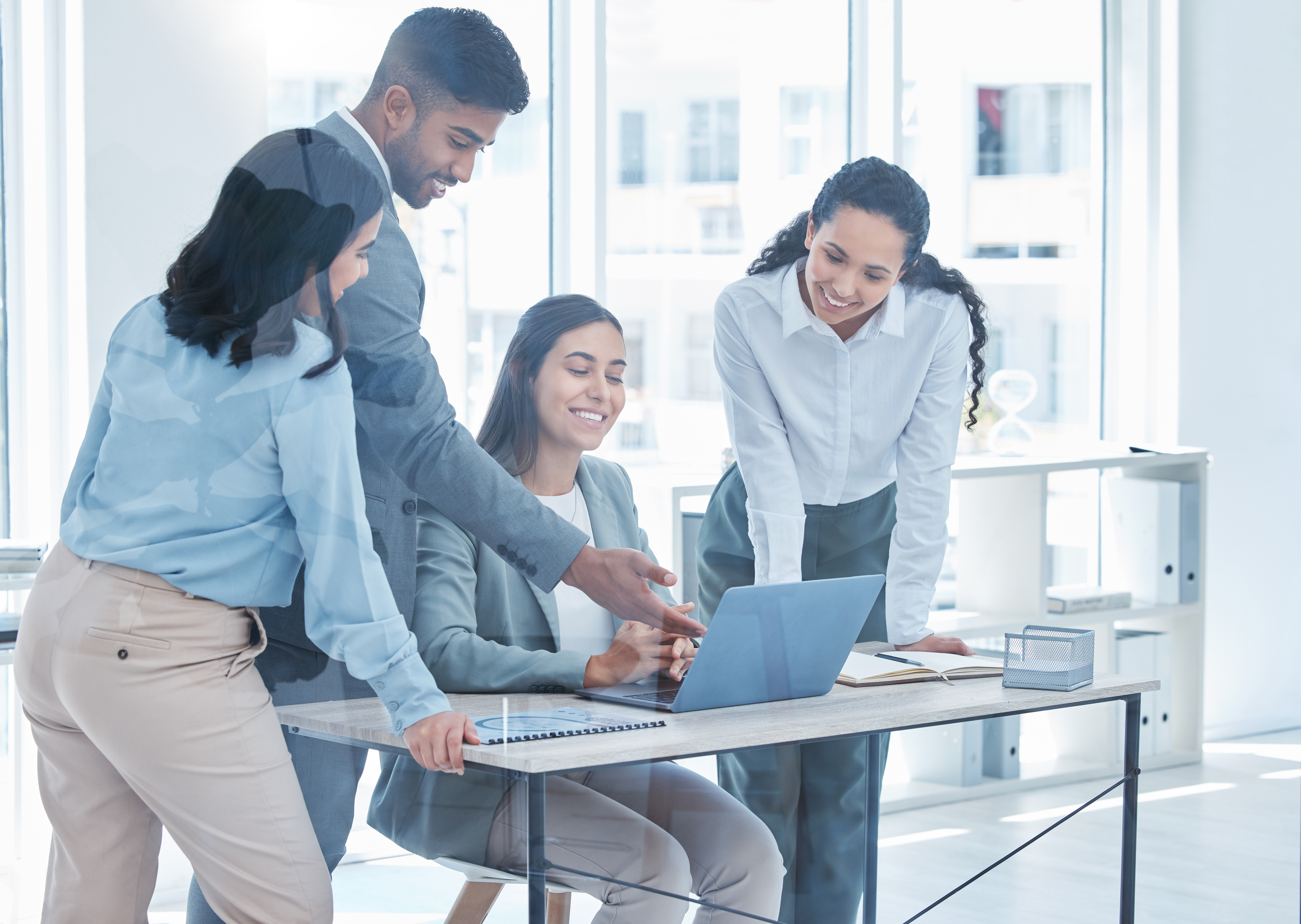 a boss looking on at her younger workers as they present something on their laptop