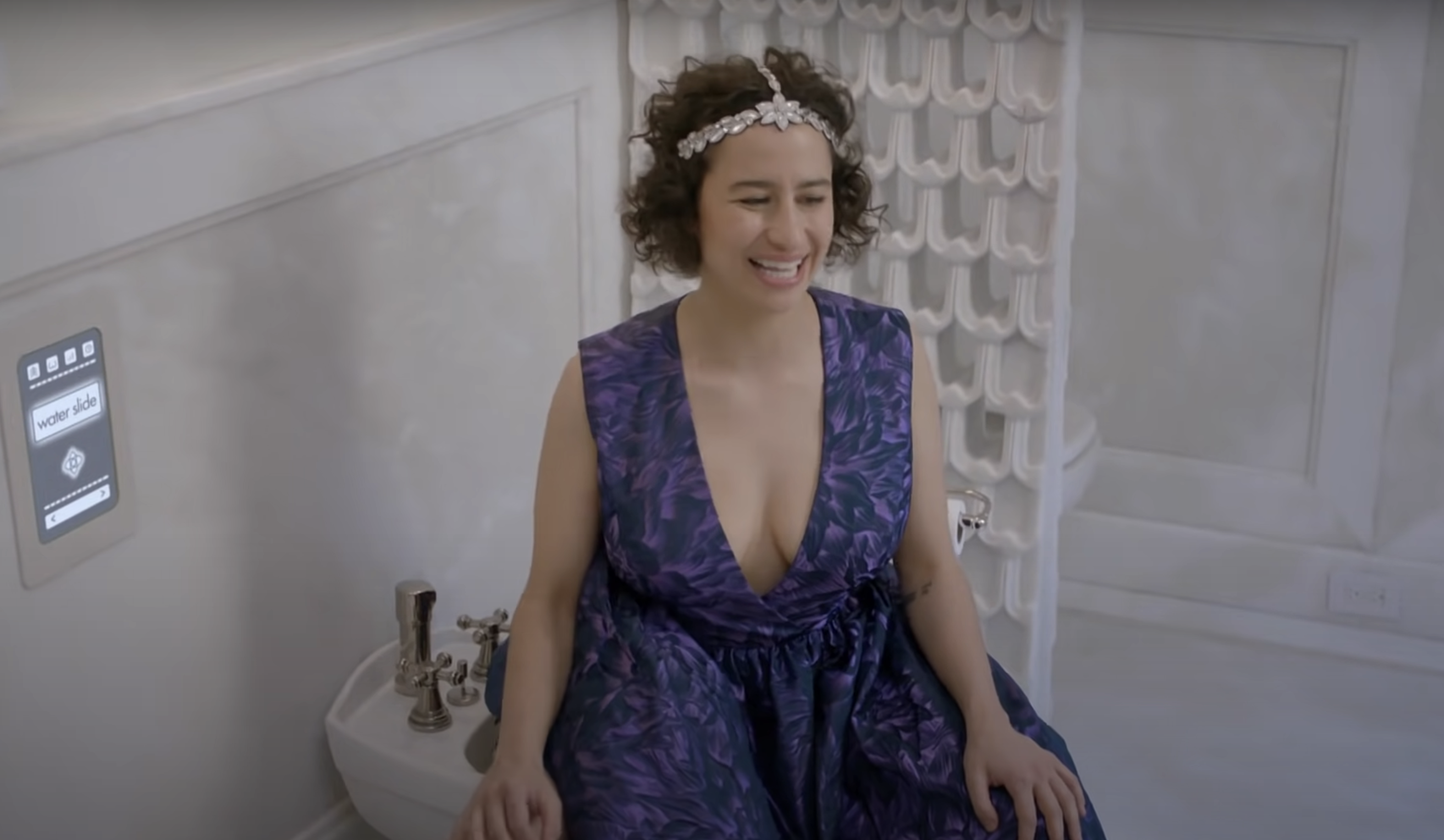 Ilana from Broad City smiling and sitting on a bidet