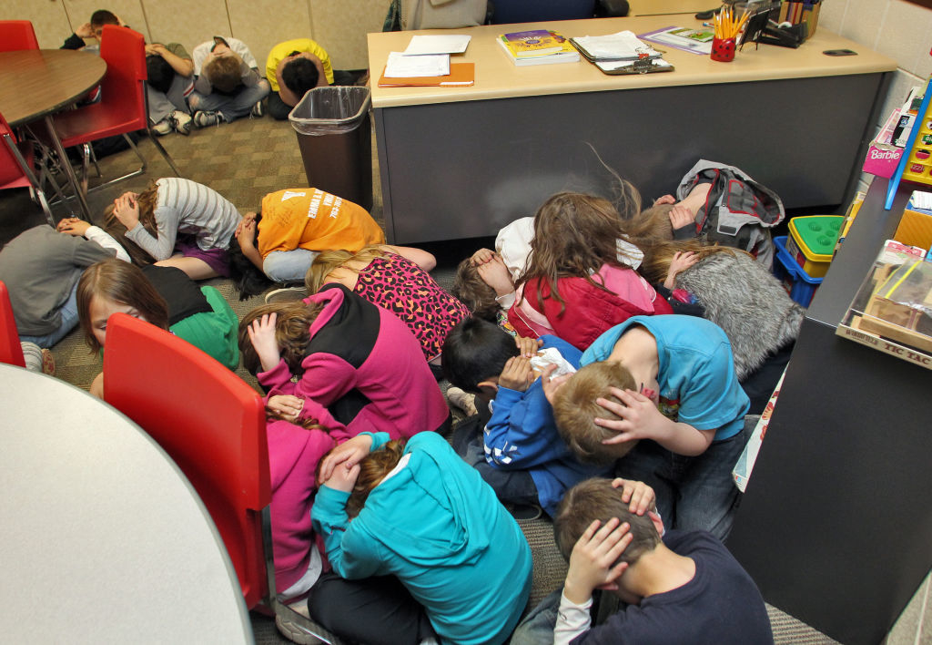A tornado drill in the US where kids are holding their head down and sitting on the ground