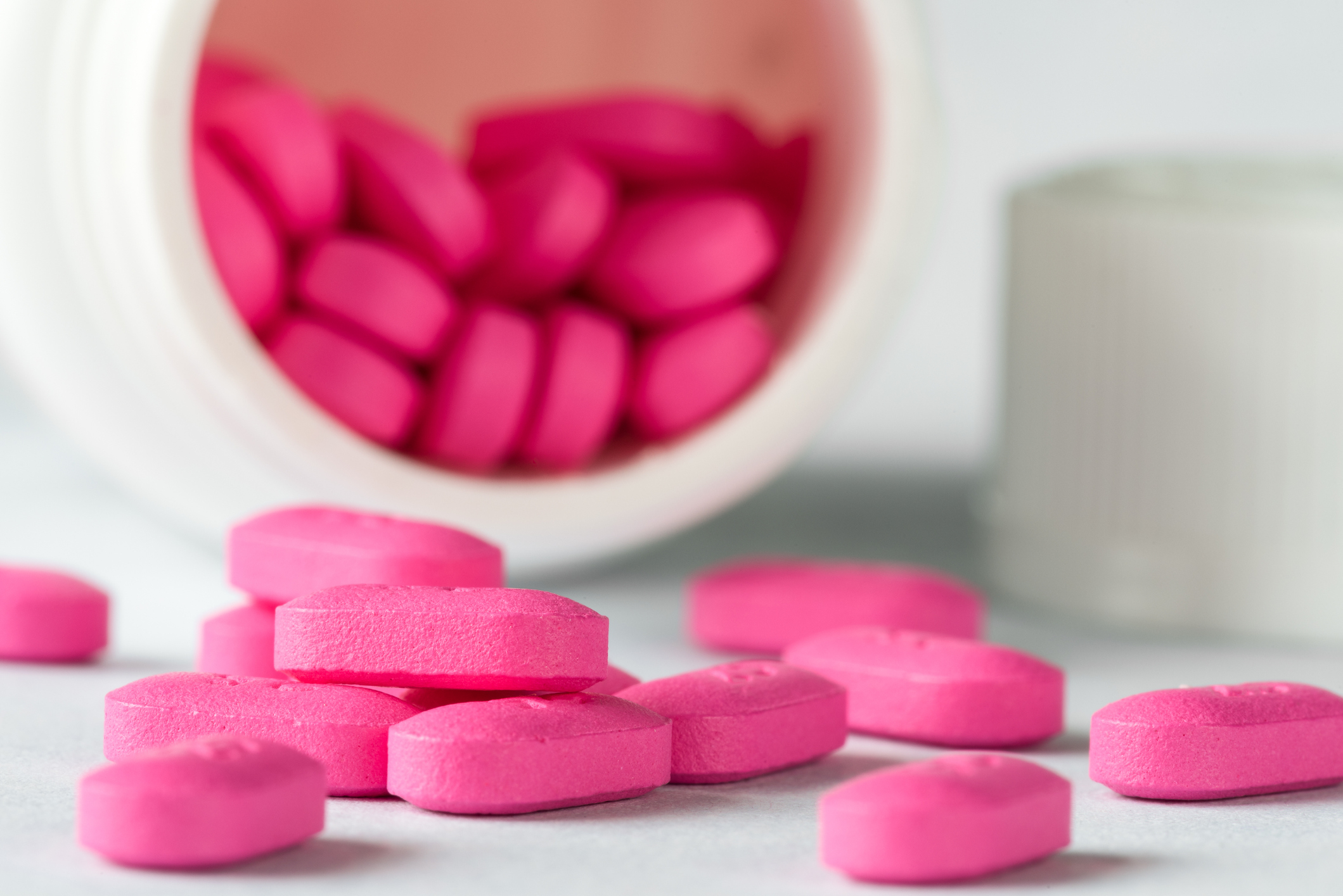 Close-up of pink tablets emerging from a bottle