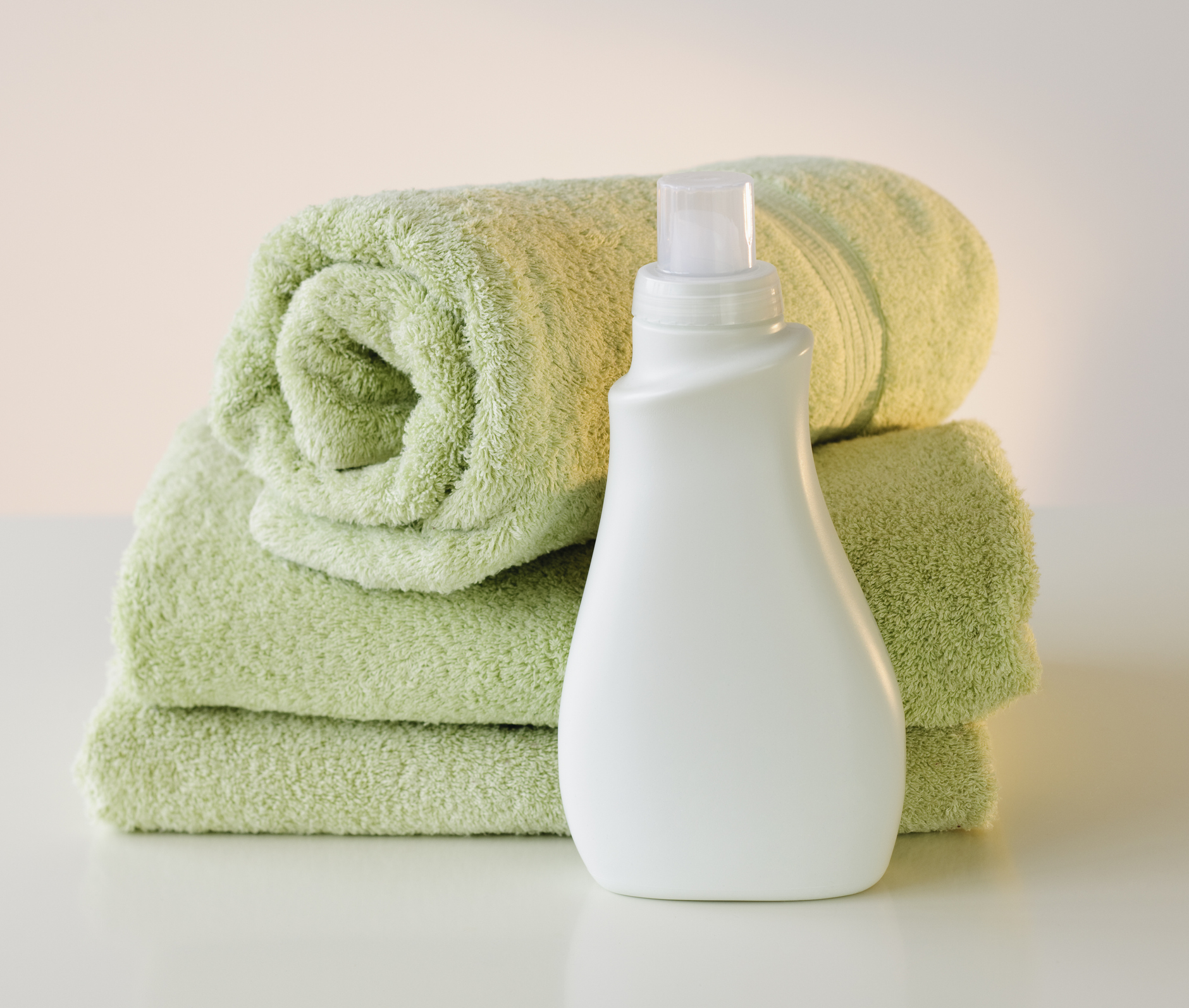 A bottle of laundry detergent next to some towels