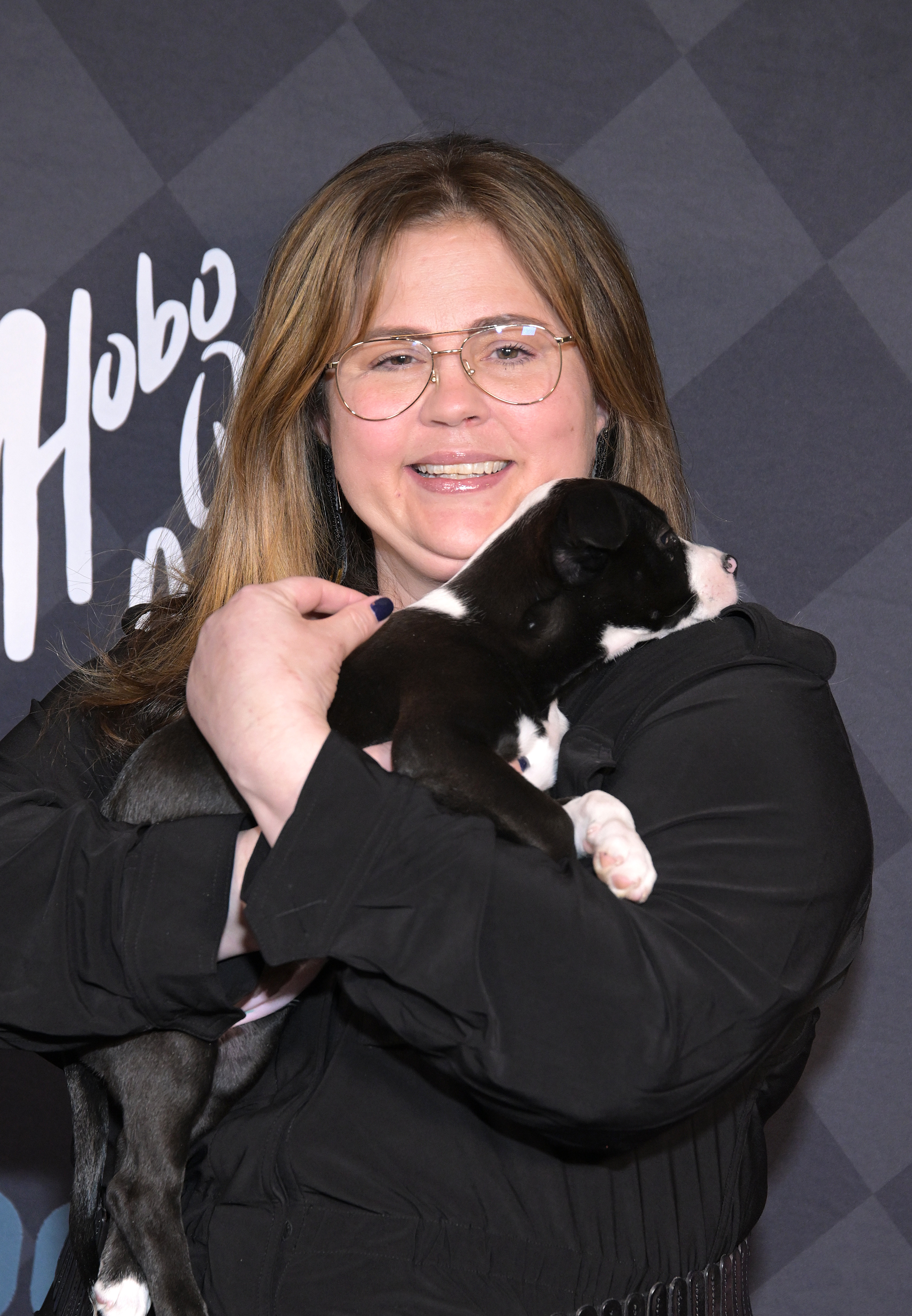 Close-up of Mandy smiling at a media event and holding a puppy