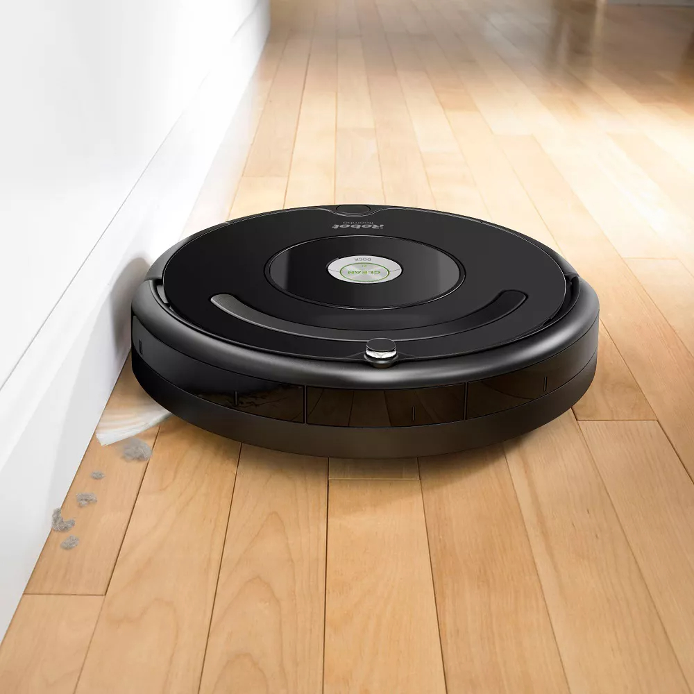Black Roomba vacuum on hardwood floor