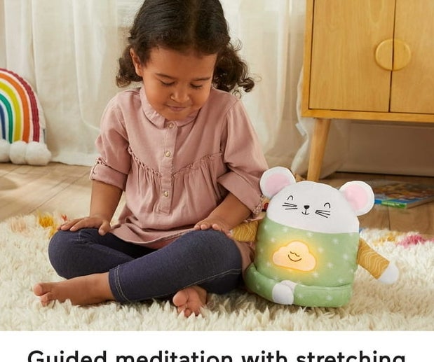 a child sitting cross legged with eyes closed next to the plush mouse