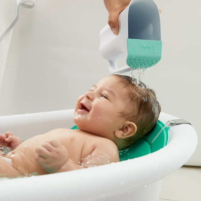 baby in a bathtime getting hair washed with shower cup