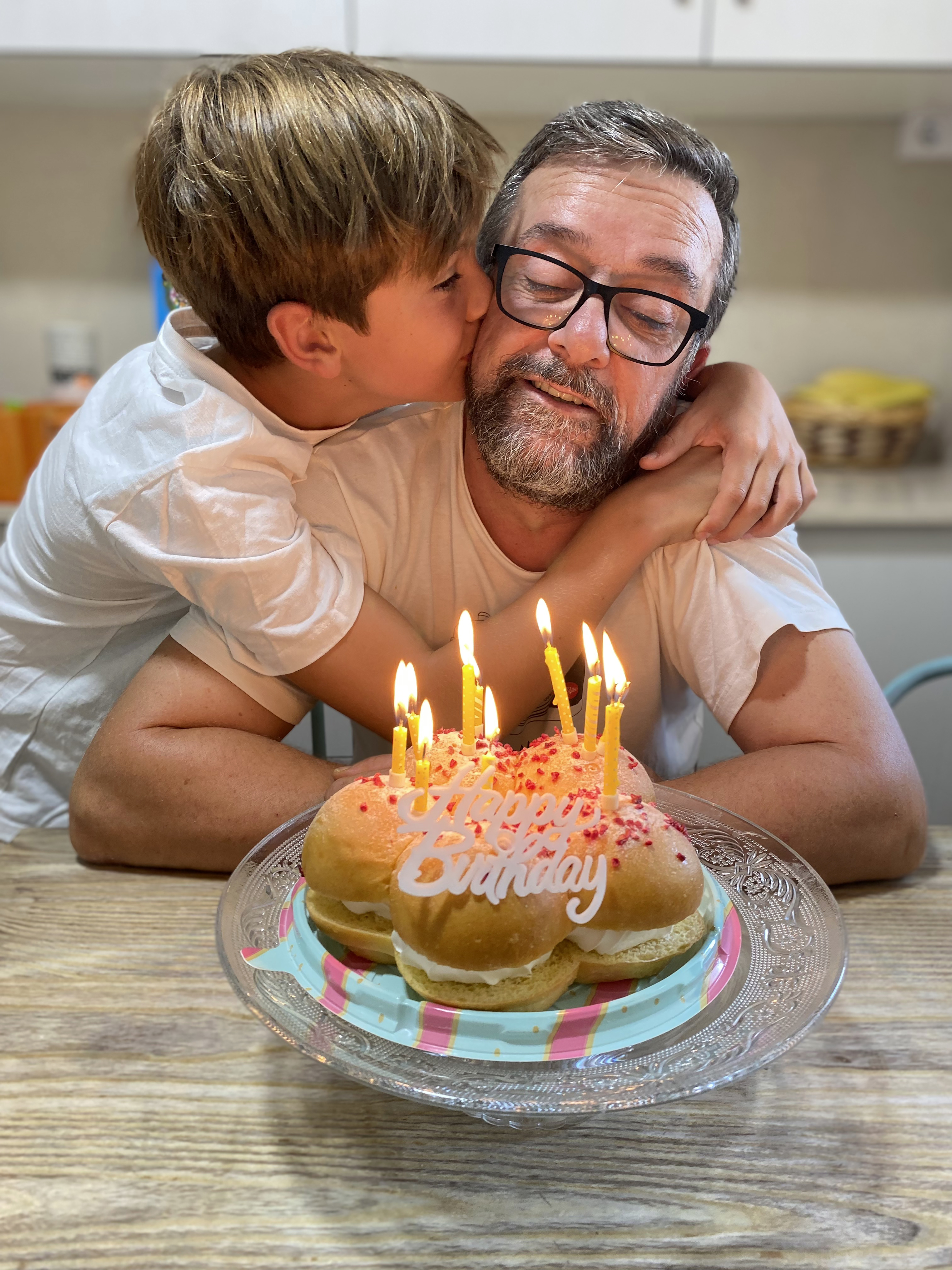 man blowing out birthday cake with child