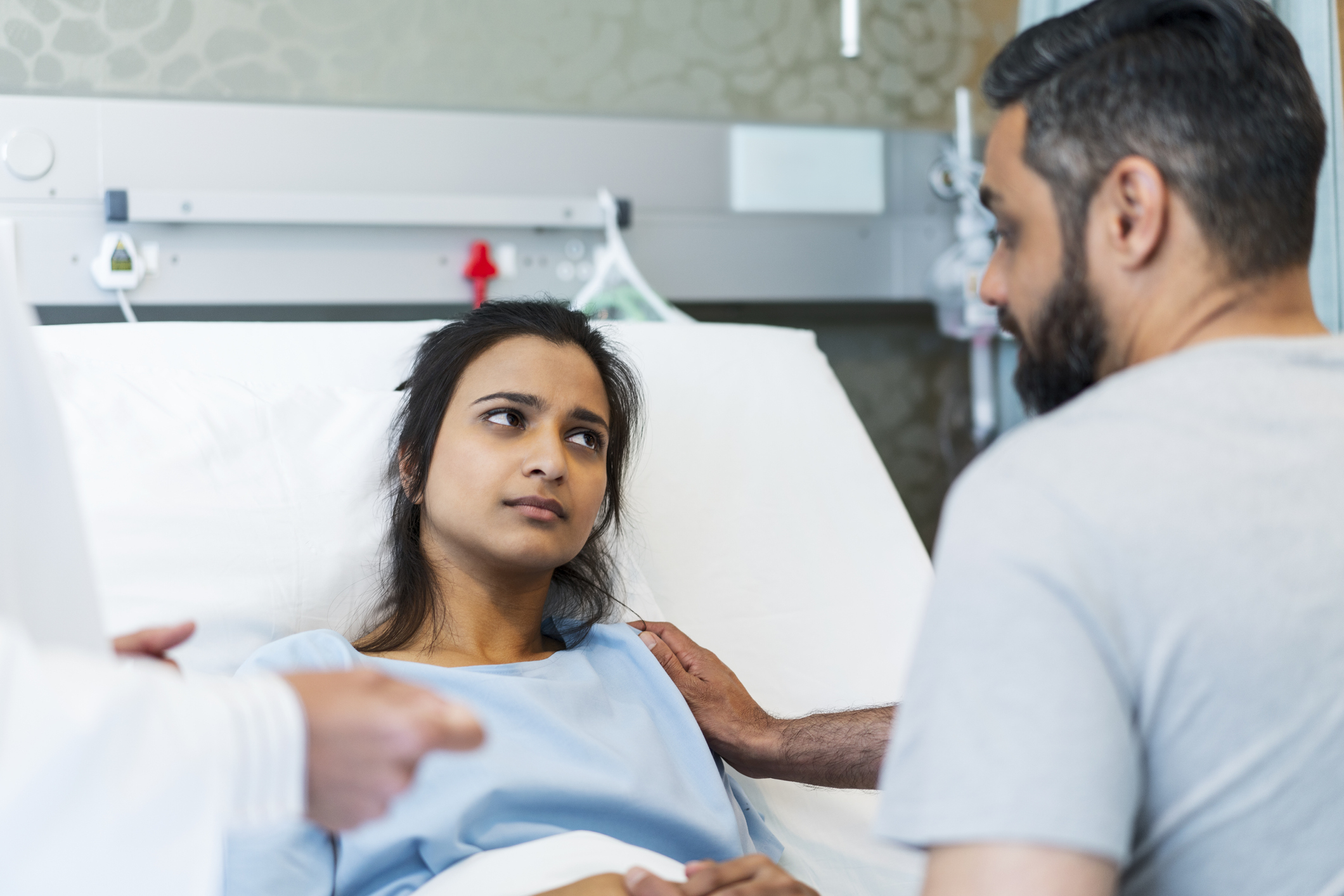 woman in hospital bed giving disapproving look to husband