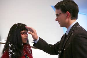 Christopher Gorham wiping fake snow off of America's Ferrera's head as Henry and Betty on Ugly Betty