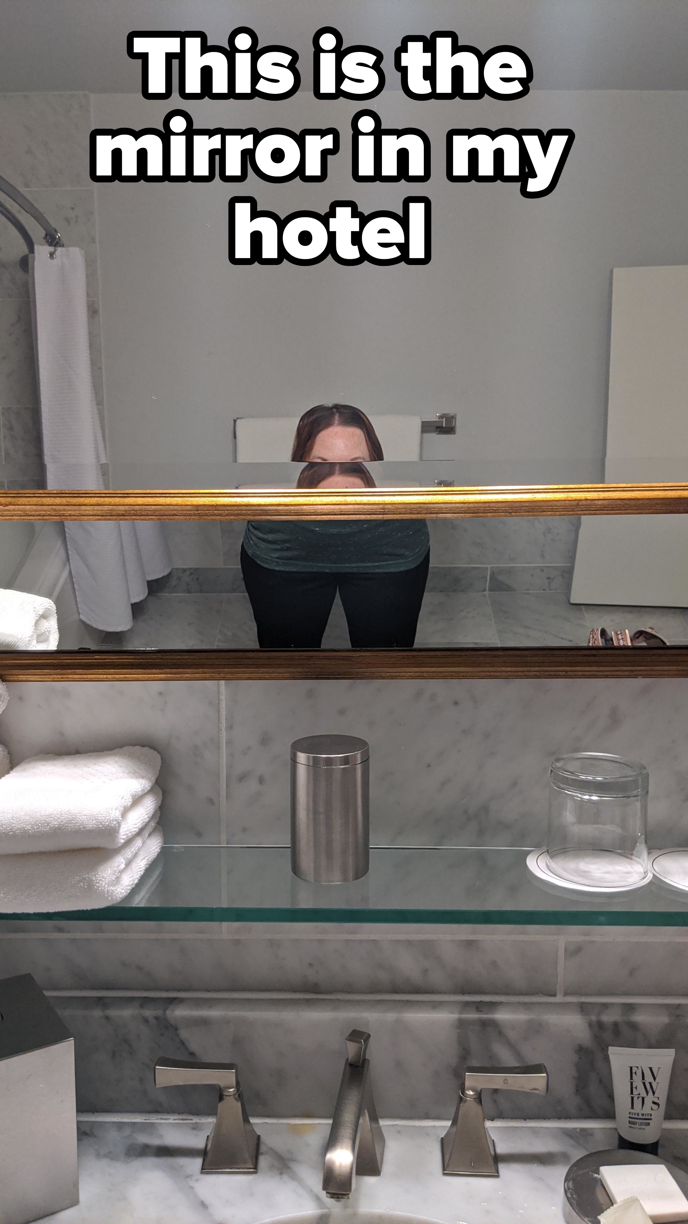 A hotel bathroom mirror that cuts off the image of a short person