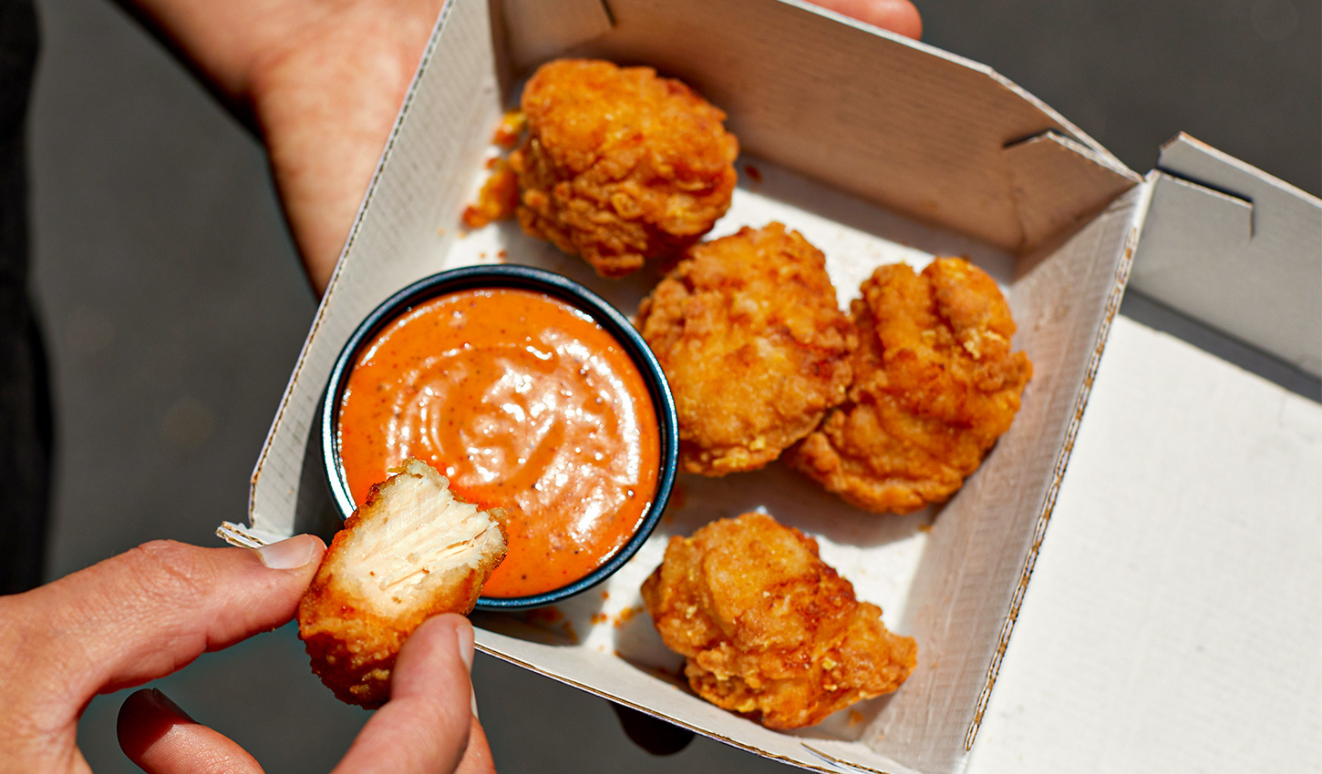 a chicken nugget being dipped in sauce