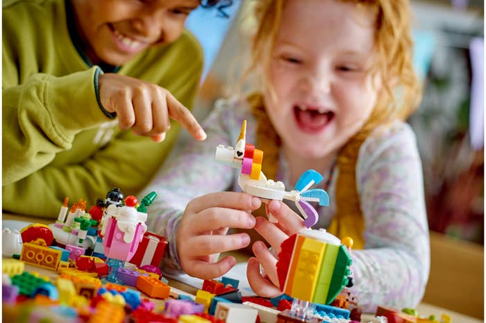 Two young kids play with a unicorn LEGO set