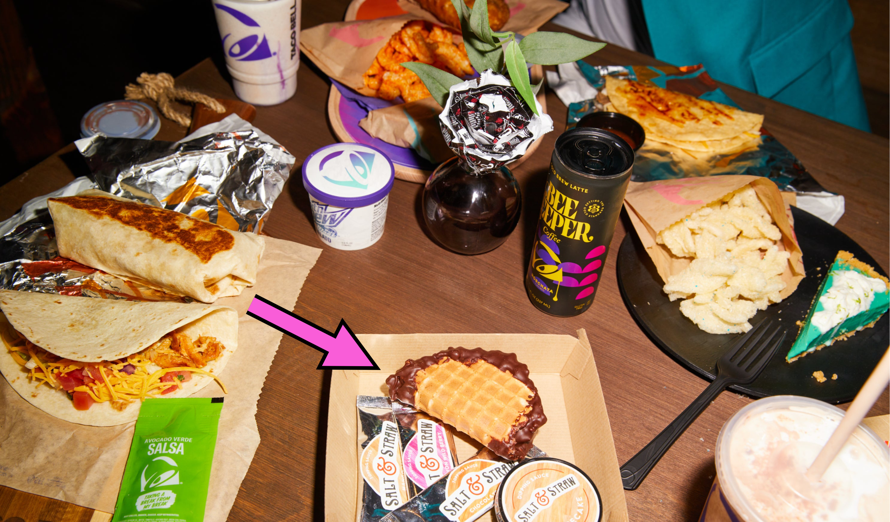 a table full of new taco bell menu items including an arrow pointing to a choco taco