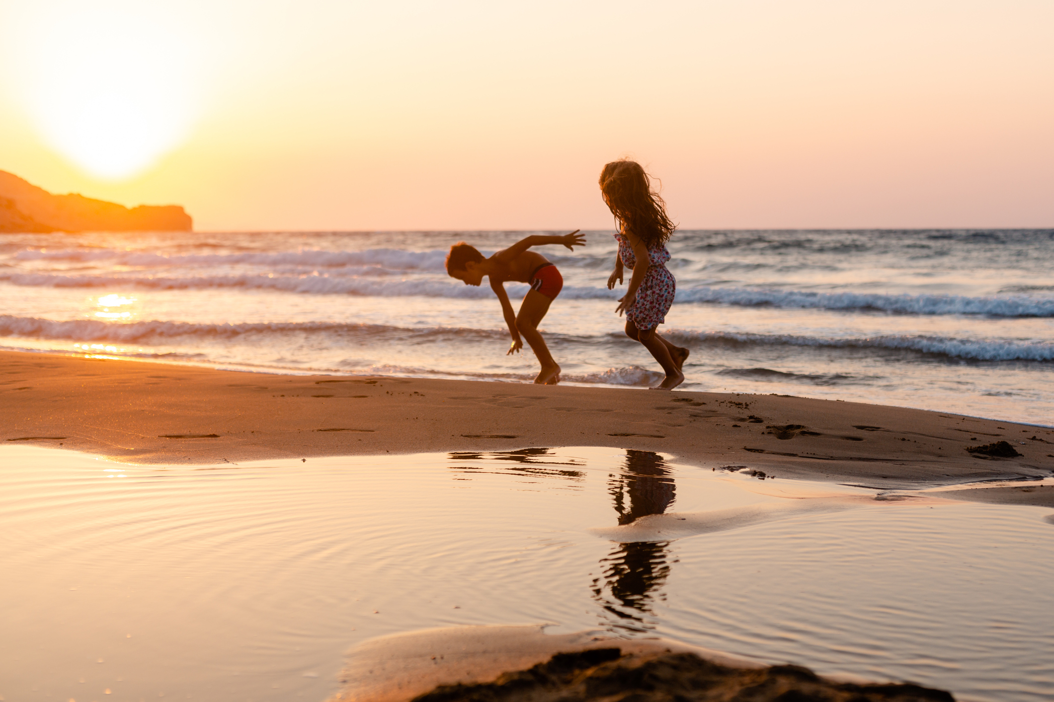 Cheerful children playing on the beach on a beautiful sunset