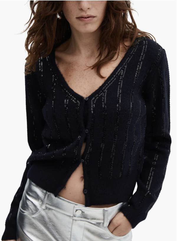 a model wearing the black sequin cardigan with a silver skirt
