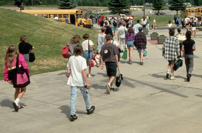 Students head toward school buses waiting in the parking lot at the end of a school day