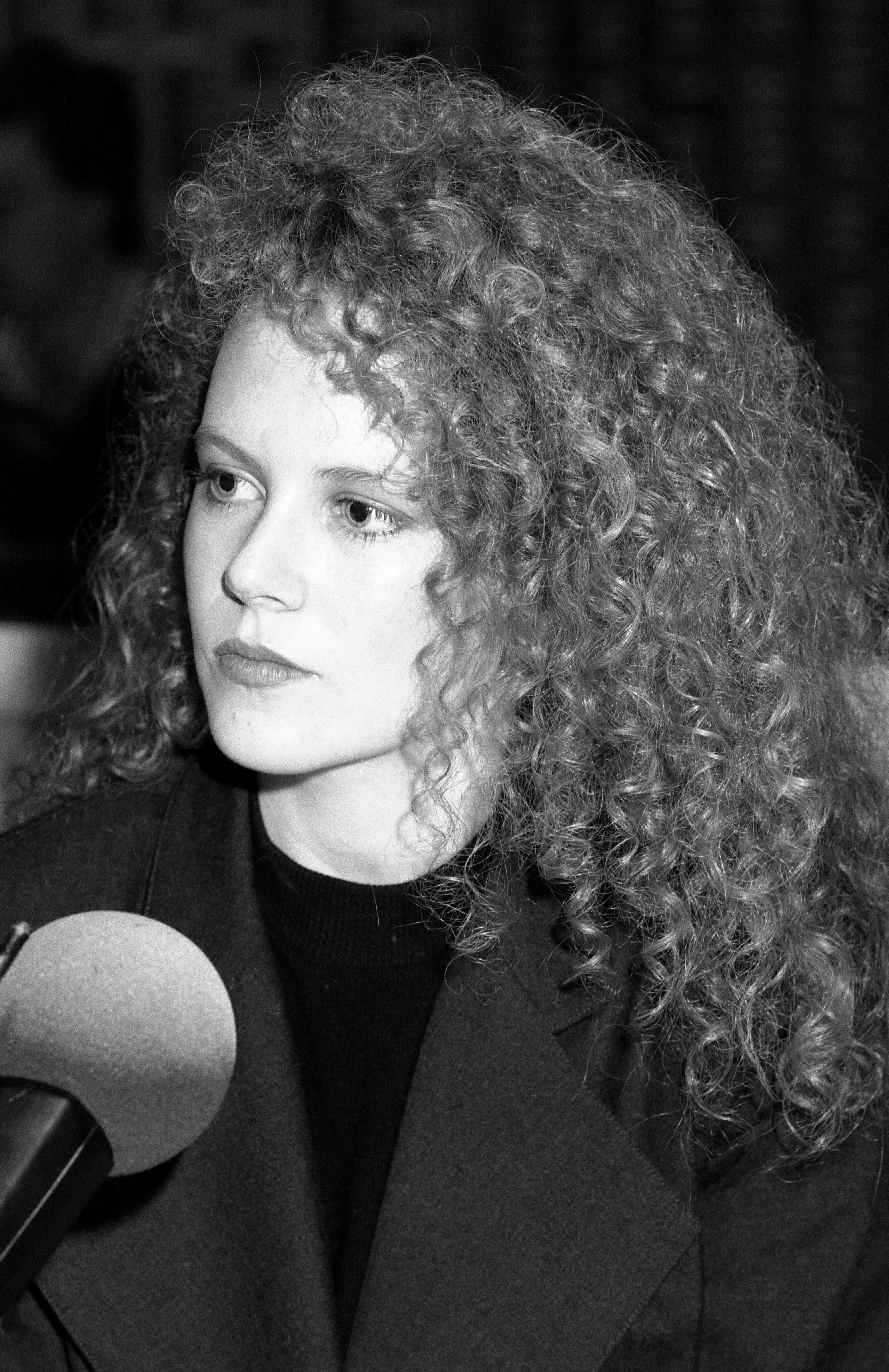 With long, curly hair in front of a microphone