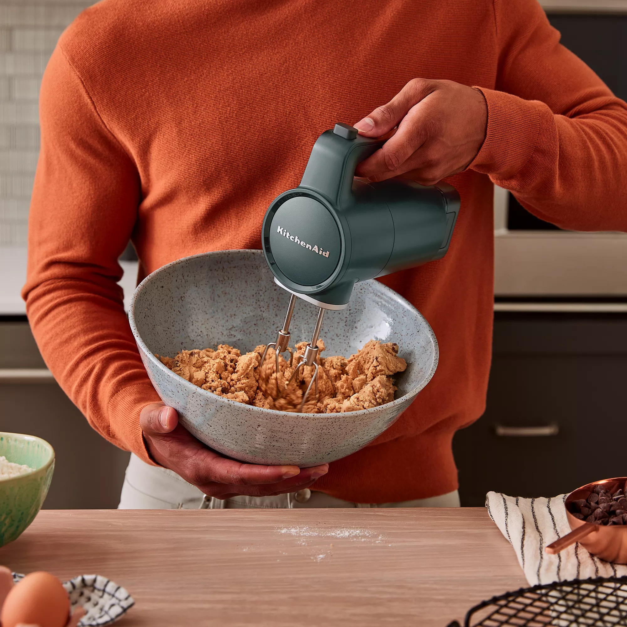 A person using the cordless mixer in a dark green