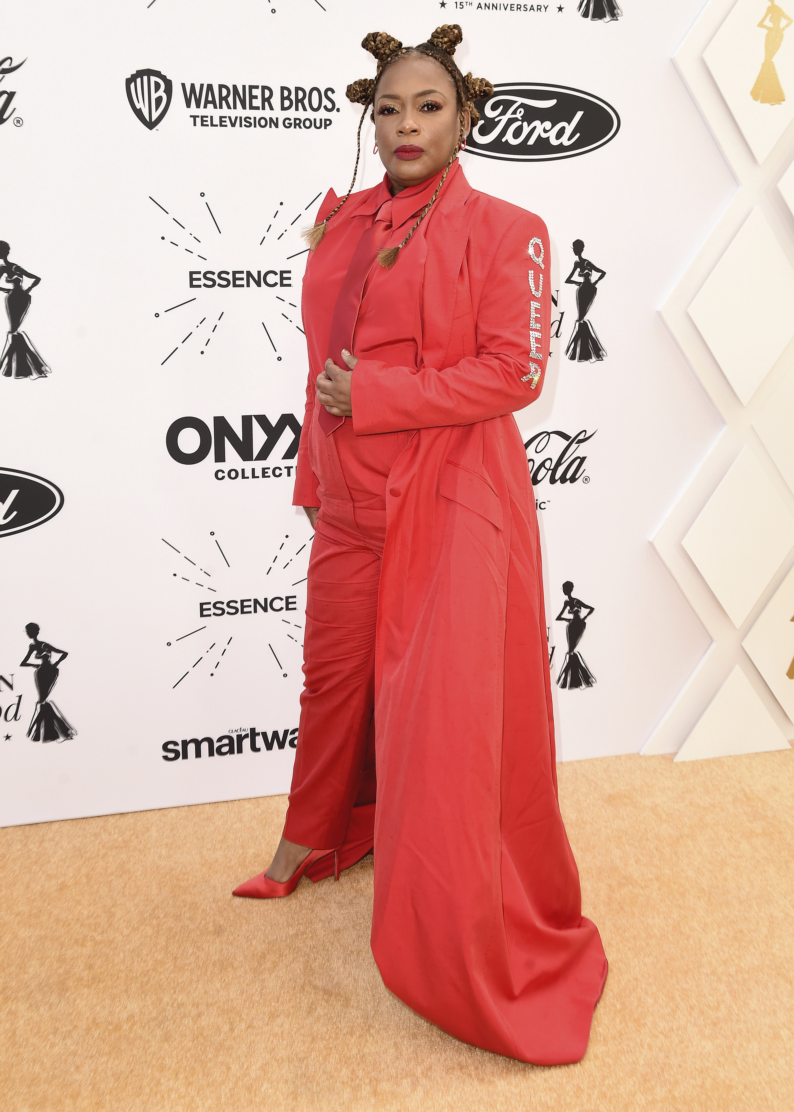 Aunjanue Ellis-Taylor in a pantsuit with a cape at an event, posing for the camera