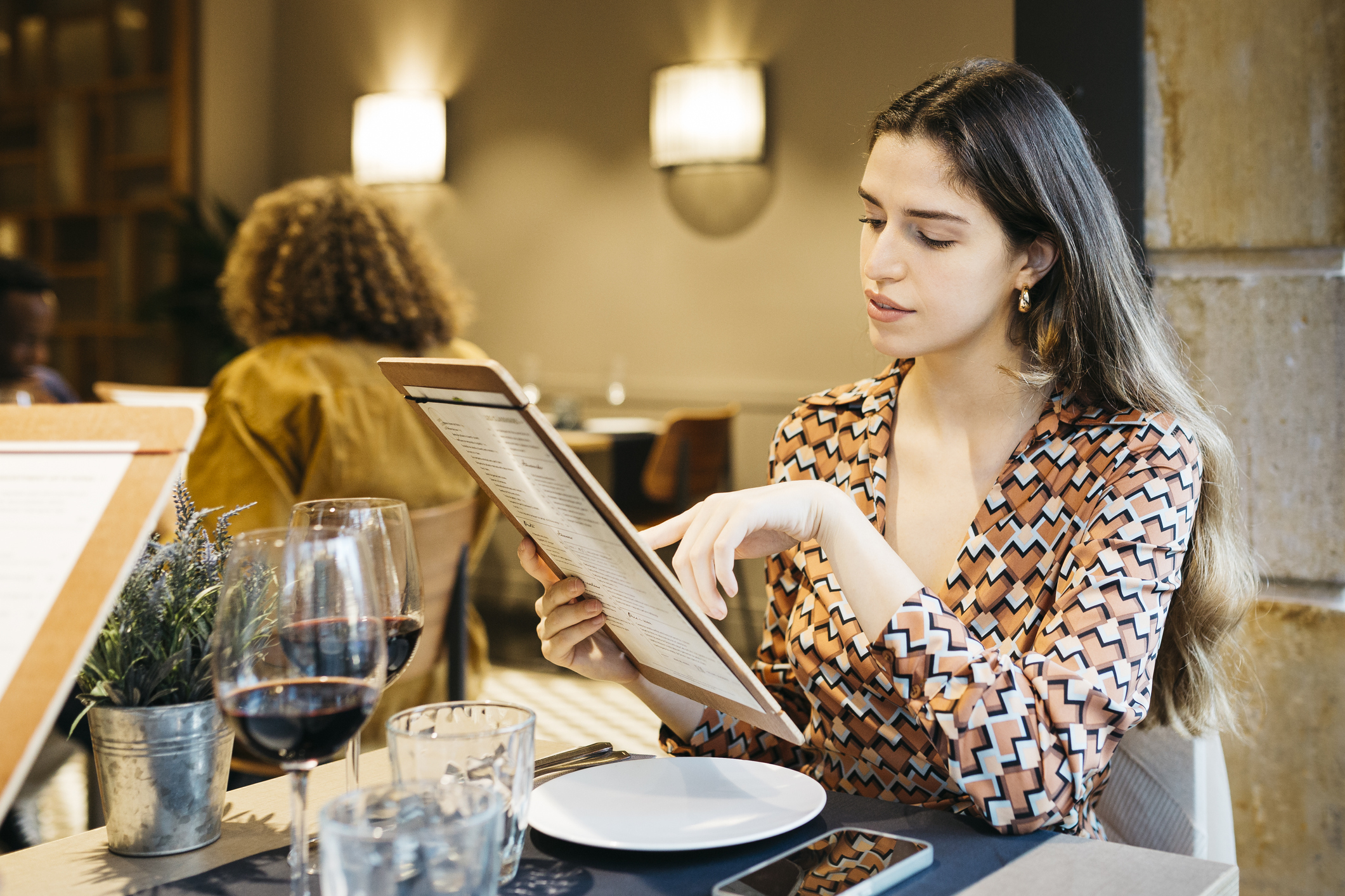 Young women sitting on a restaurant table and reading the menu